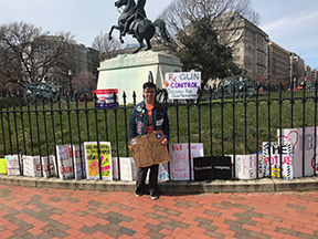 Young man standing in front of the white house amid anti-gun signs